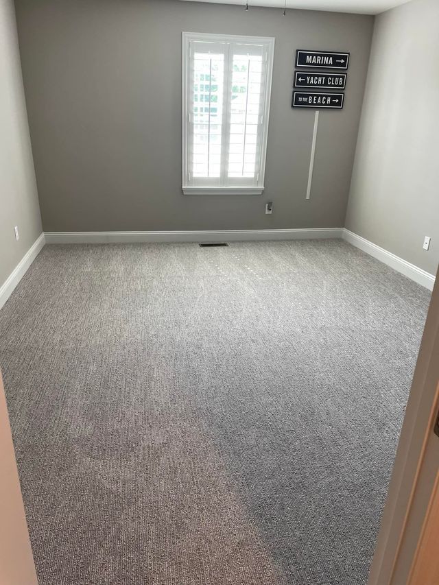 An empty room with a carpeted floor and a window.
