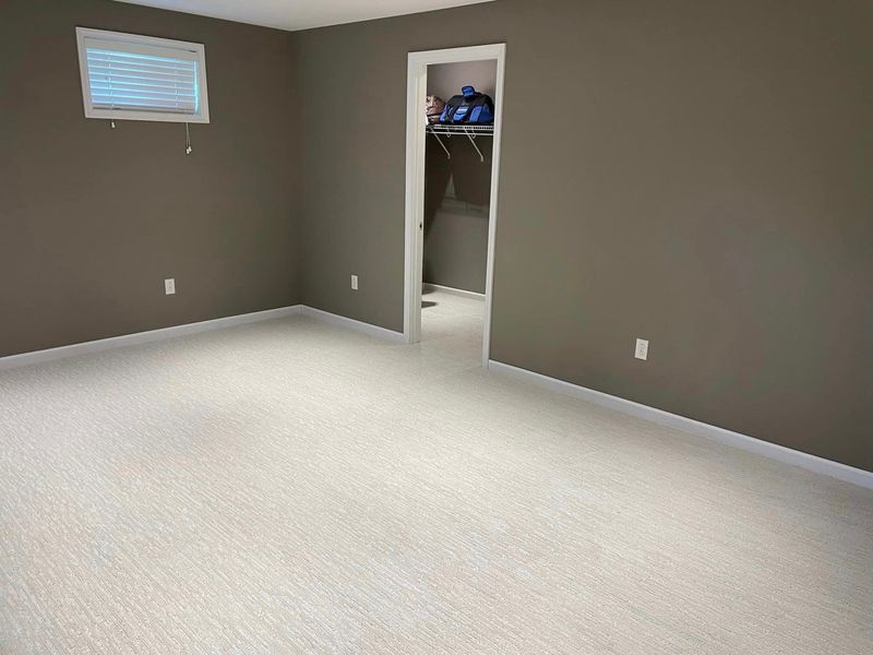 An empty room with a walk in closet and a window.