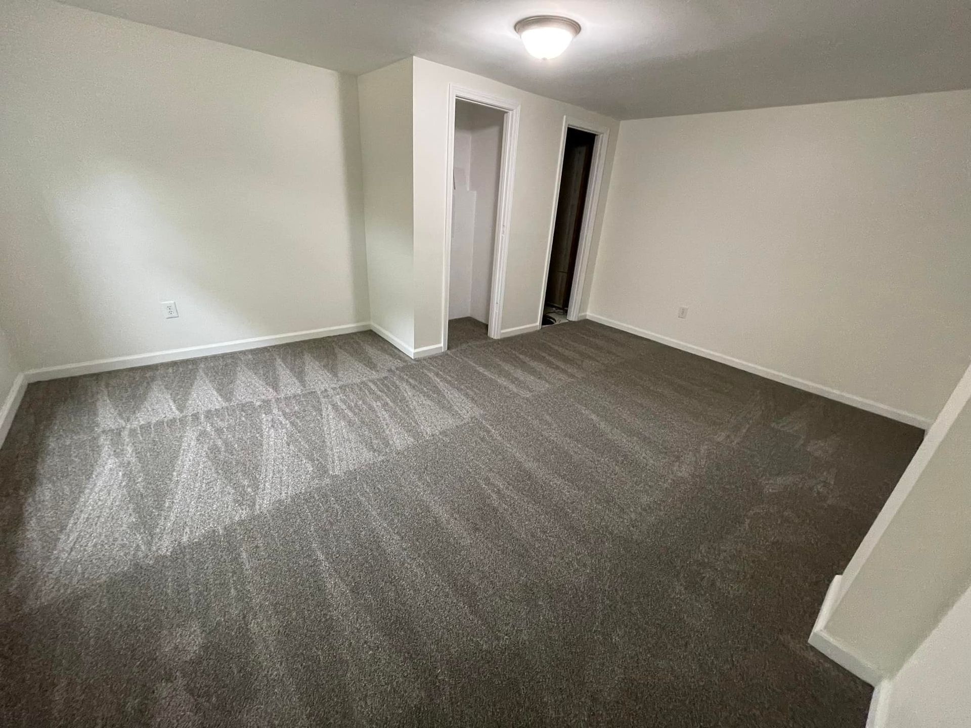 An empty room with a carpeted floor and white walls.