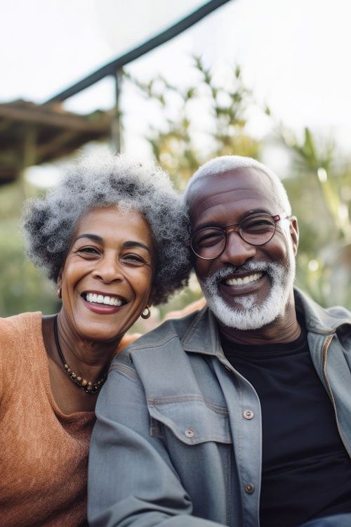 Smiling elderly Black couple outdoors, man in glasses and gray beard.