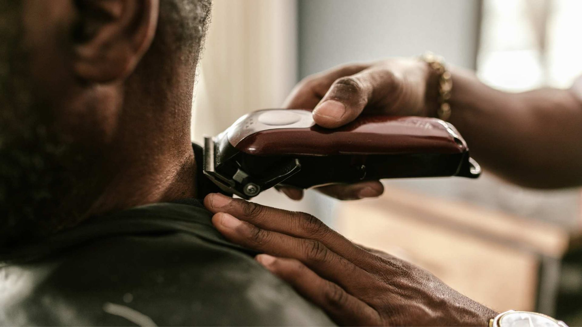 Barber using clippers to trim a person's neck.