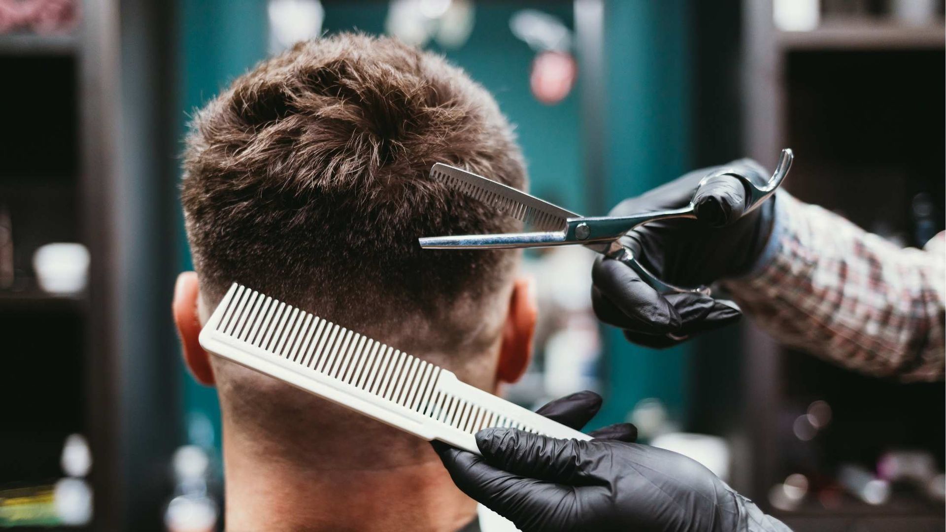 Barber cutting hair with scissors and comb.