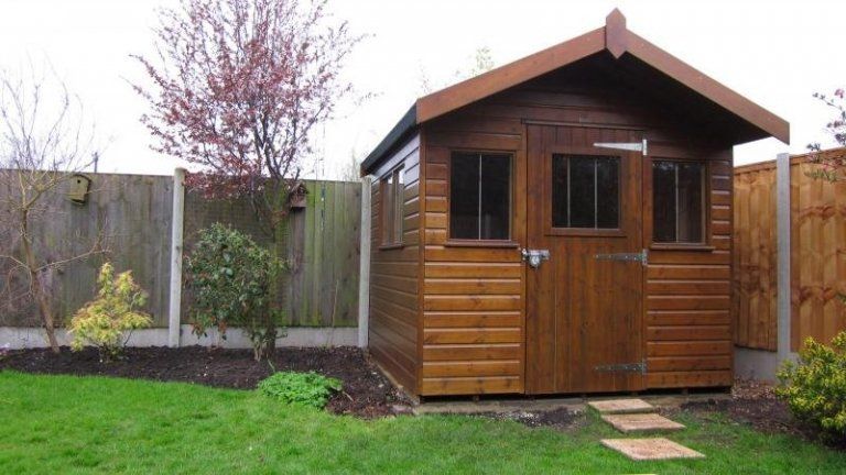 Brown garden shed in small garden, painted by Hedon Exterior Cleaning.