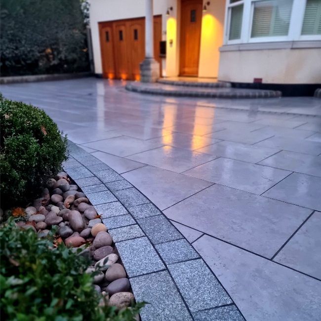 Modern paving slab driveway, edged with cobbles.