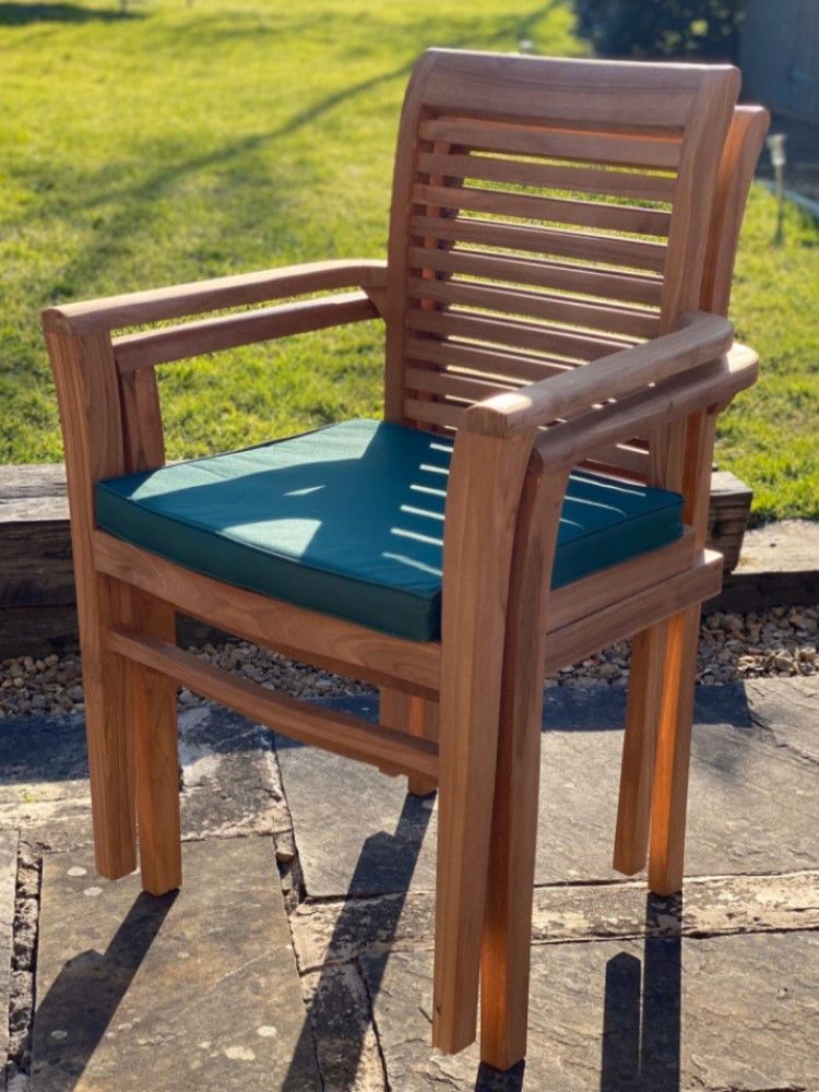 Two stacked teak garden patio chairs that have been professionally refinished through our restoration process