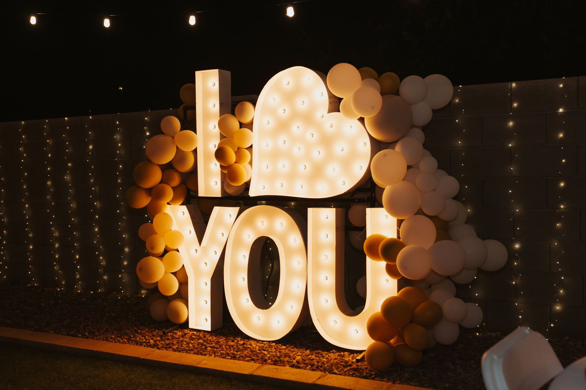 a large lighted sign that says `` i love you '' is surrounded by balloons .