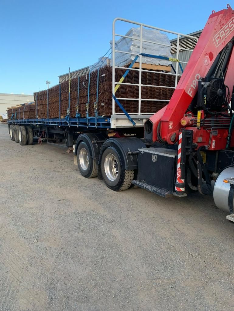 A red truck with a crane attached to it is parked on the side of the road — White's Truck & Machinery Hire in Bouldercombe, QLD