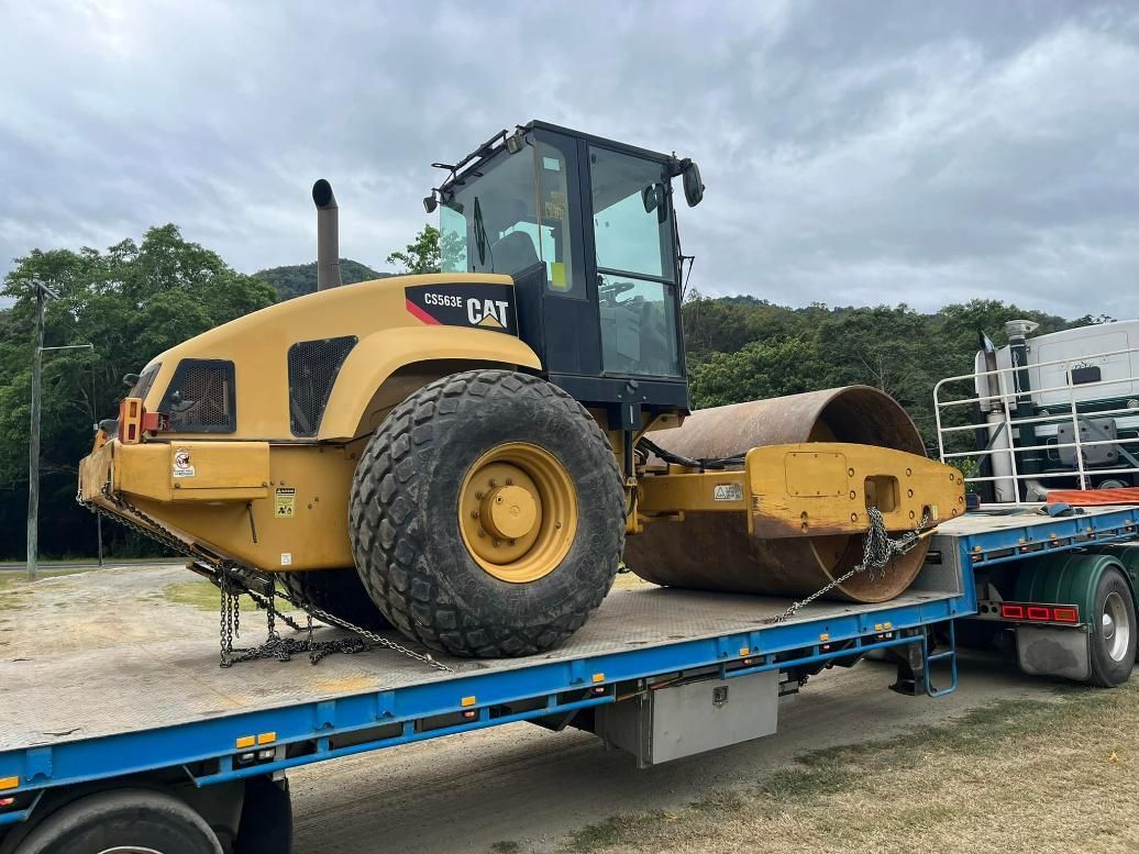A Yellow Cat Roller Is Sitting on Top of A Blue Trailer — White's Truck & Machinery Hire in Bouldercombe, QLD
