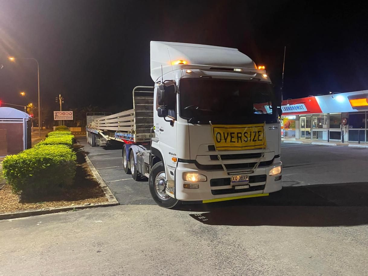 An oversize truck is parked in a parking lot at night — White's Truck & Machinery Hire in Bouldercombe, QLD