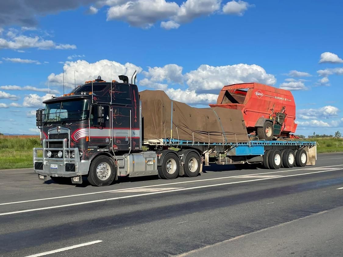 A semi truck is driving down a highway with a trailer attached to it.