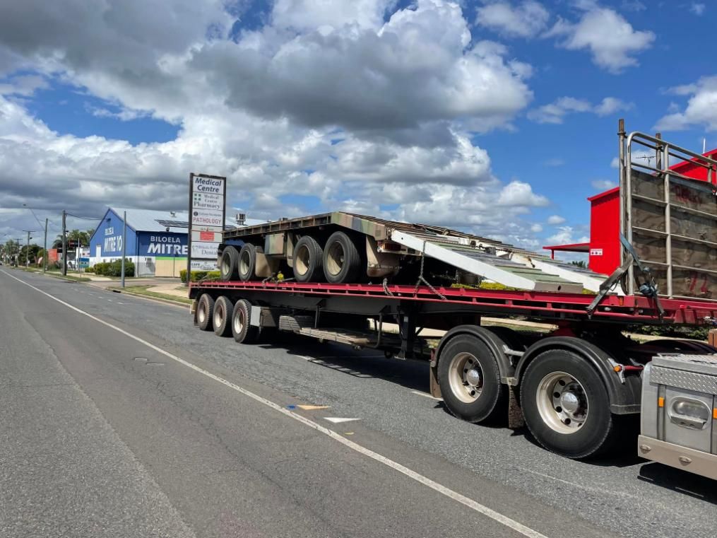 A Semi Truck Is Driving Down a Road with A Ramp Attached to It — White's Truck & Machinery Hire in Bouldercombe, QLD