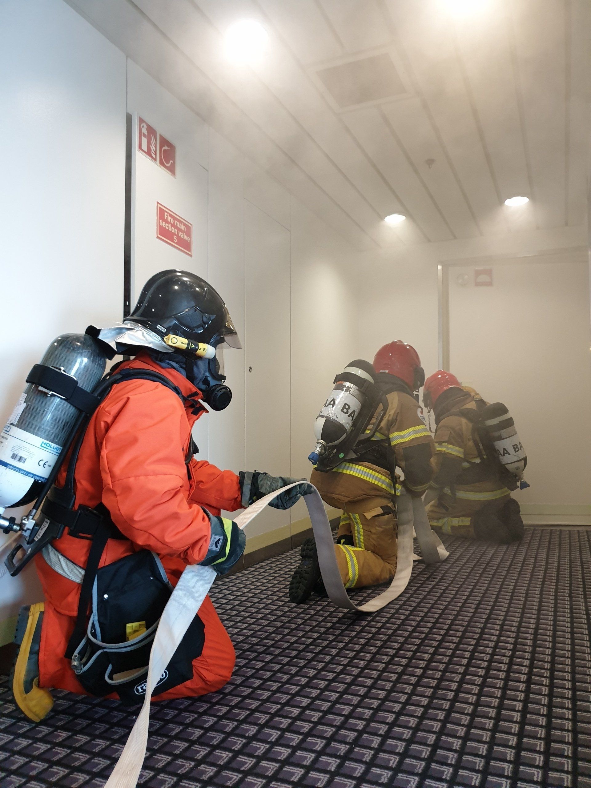 Firefighters conducting firefighting on board of a passenger ship assisted by the ships fireteam. Marine firefighting, shipboard firefighting