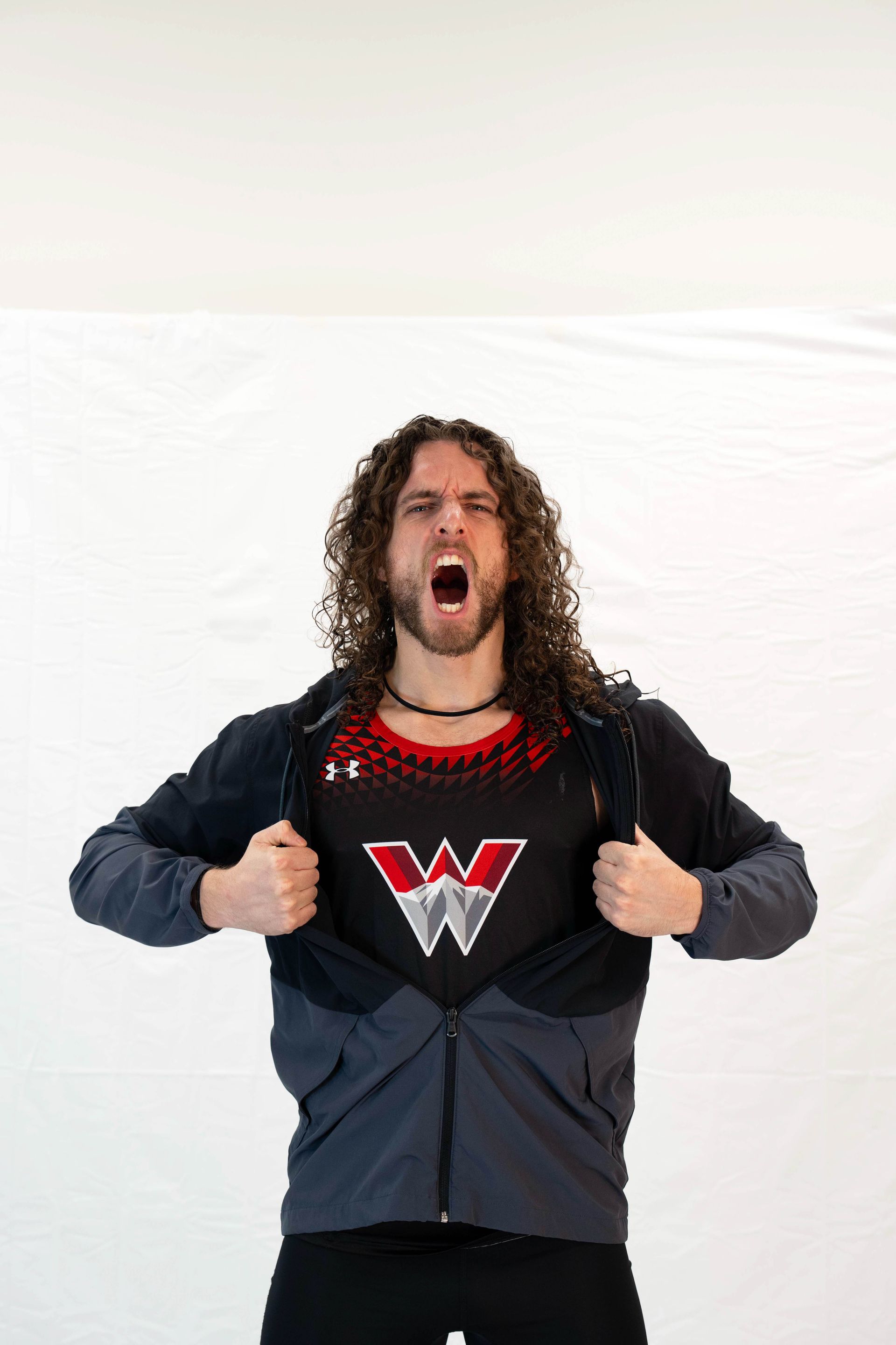 Man pulling open jacket to reveal a black shirt with a red 