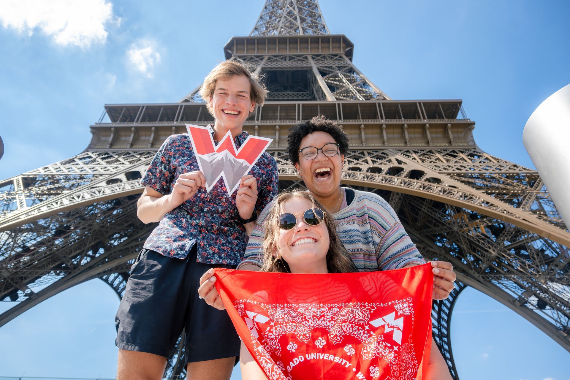 Three people in front of Eiffel Tower, holding a 