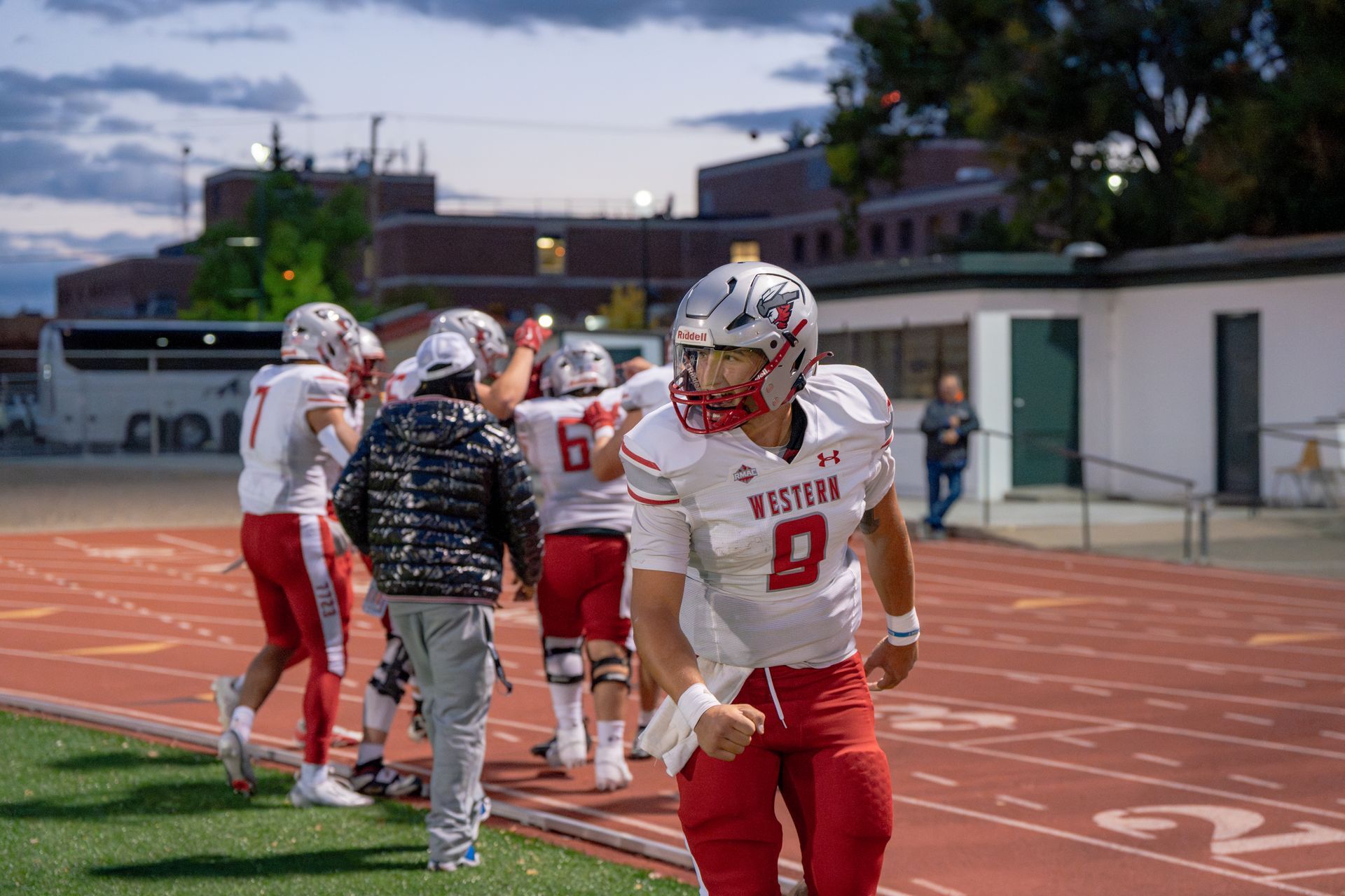 Football players in red and white uniforms celebrate on a track.