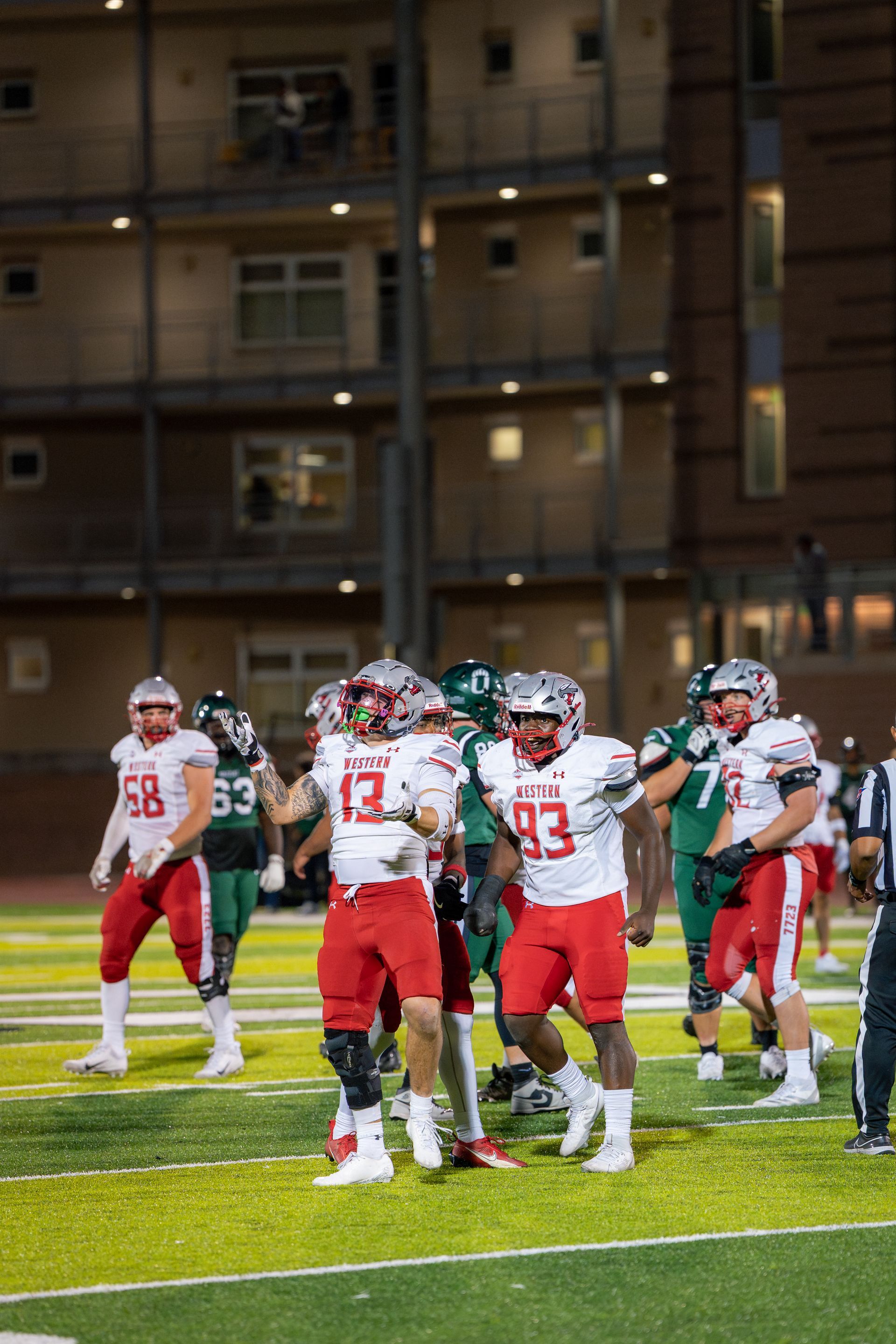 Football players in red and white uniforms celebrating on a green field.