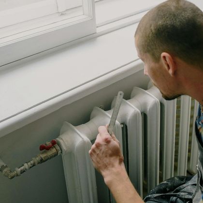 A man is working on a radiator with a wrench