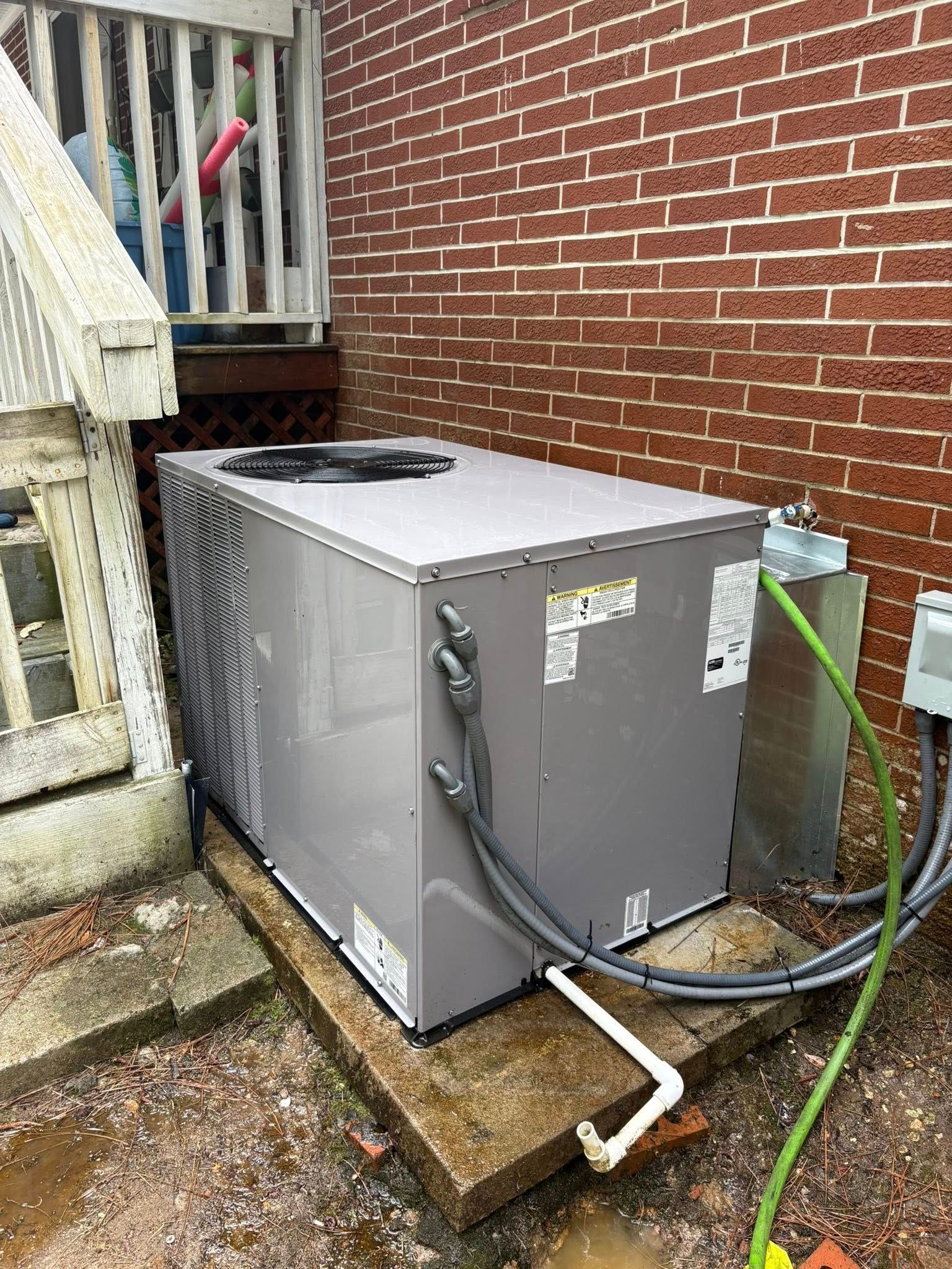 A large air conditioner is sitting on the side of a brick building.