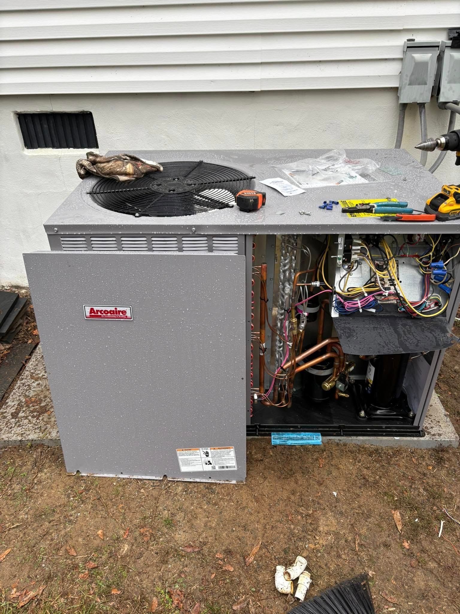 An air conditioner is being repaired in the backyard of a house.