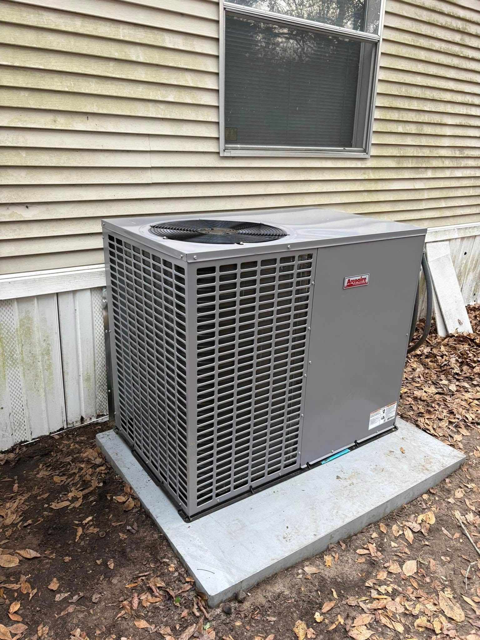 A large air conditioner is sitting outside of a house.