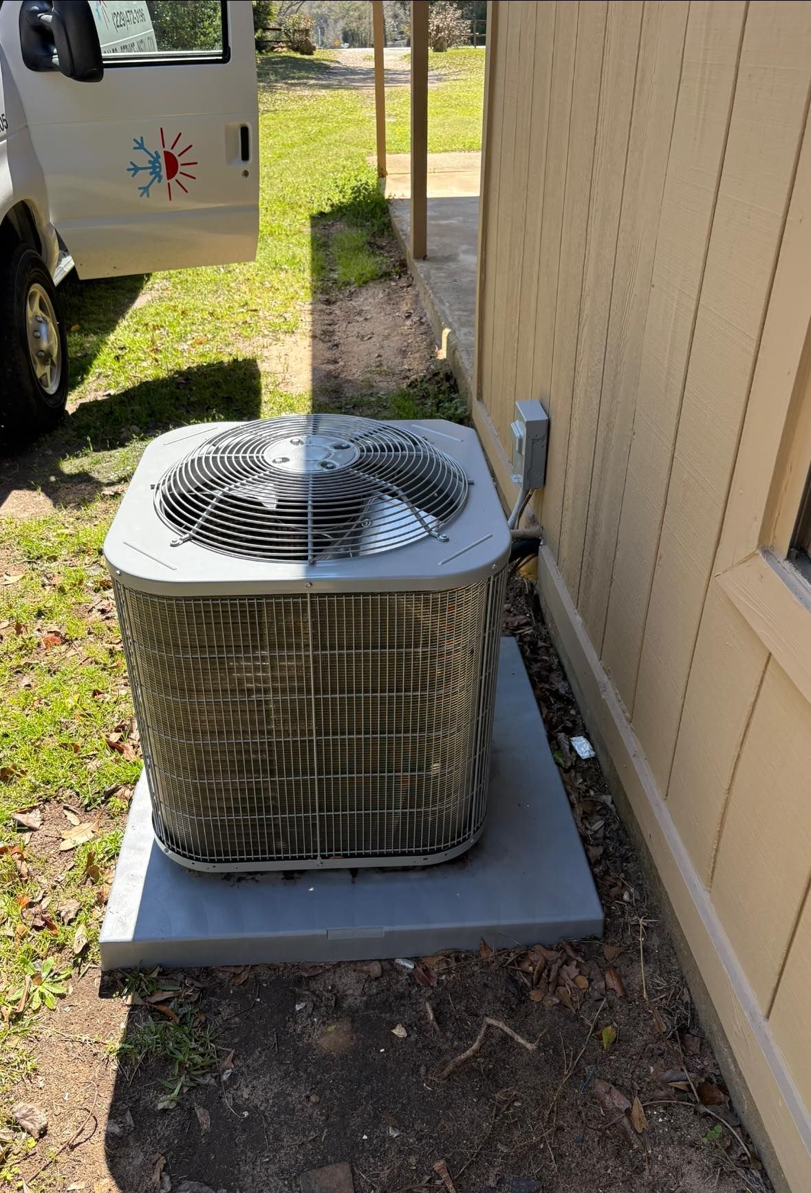 An air conditioner is sitting outside of a house next to a van.