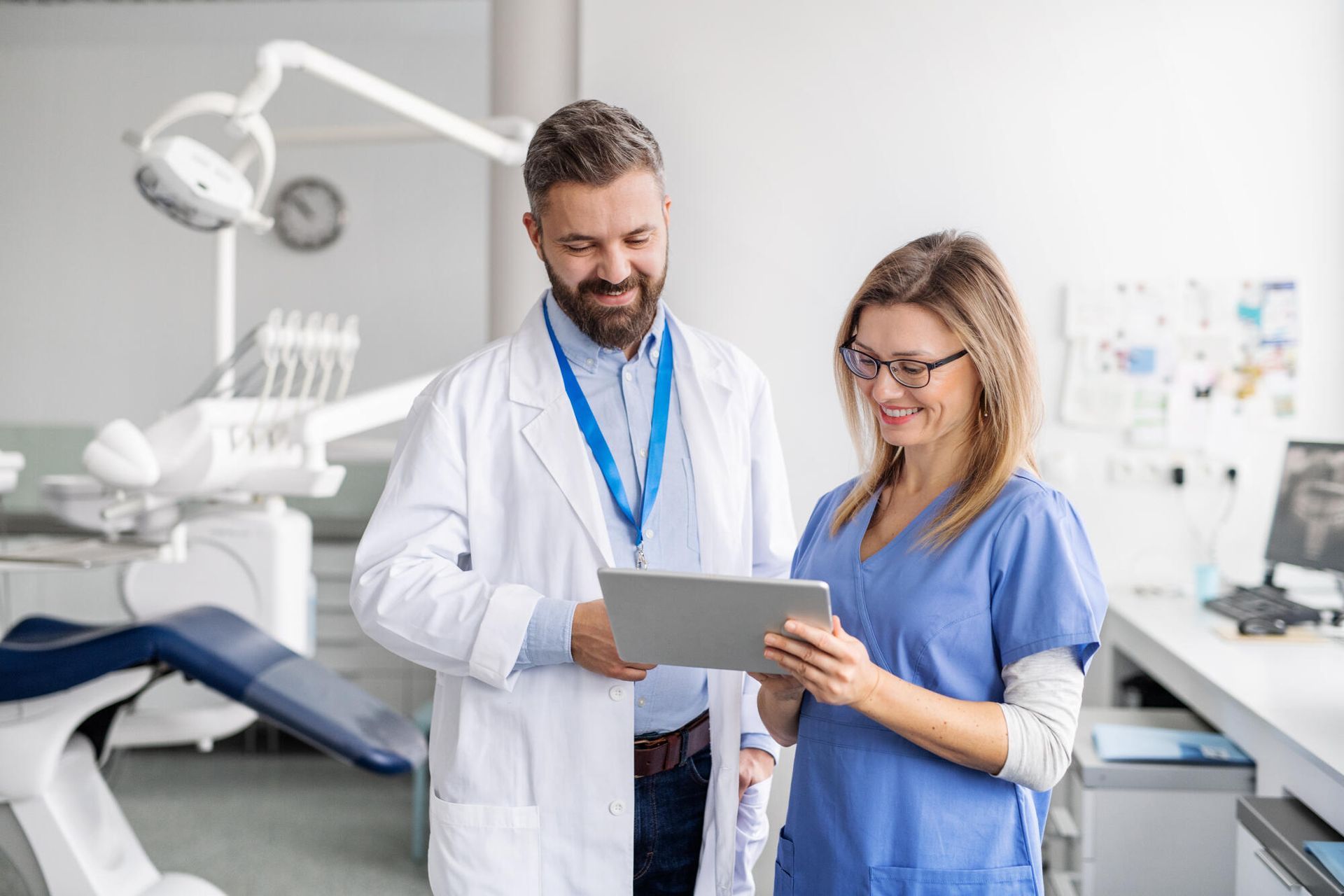 A dentist and a nurse are looking at a tablet in a dental office.