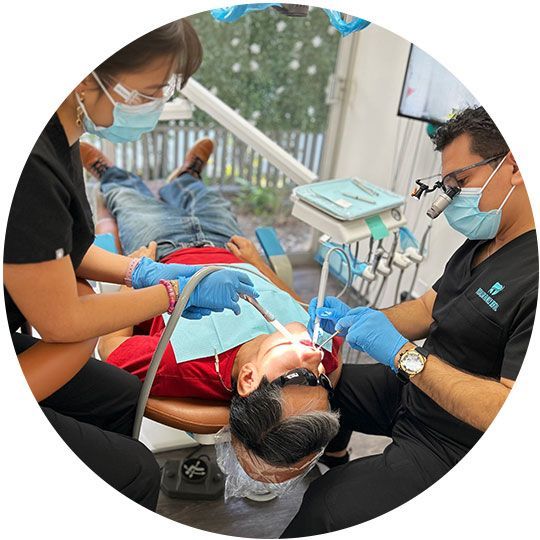 A man is getting his teeth examined by two dentists