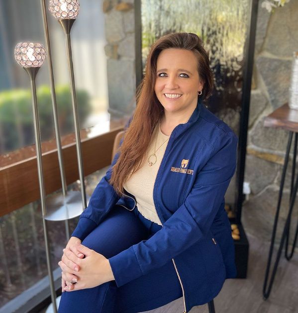 A woman in a blue jacket is sitting in front of a window