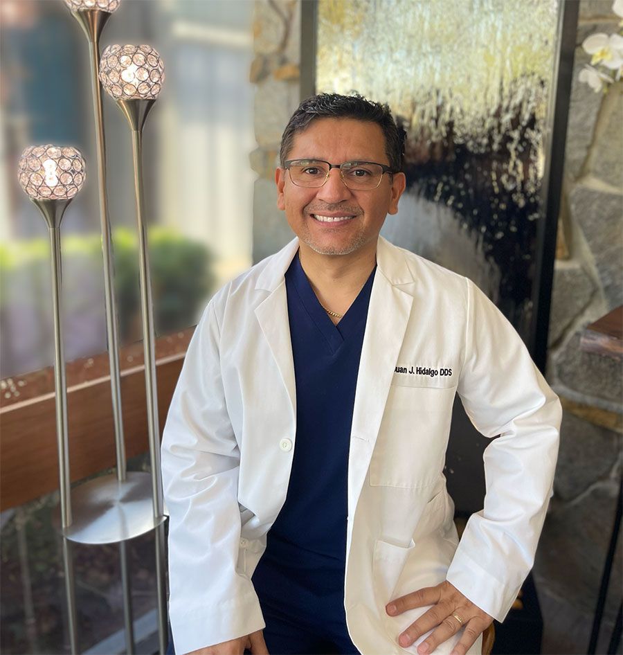 A man wearing a lab coat and glasses is smiling for the camera