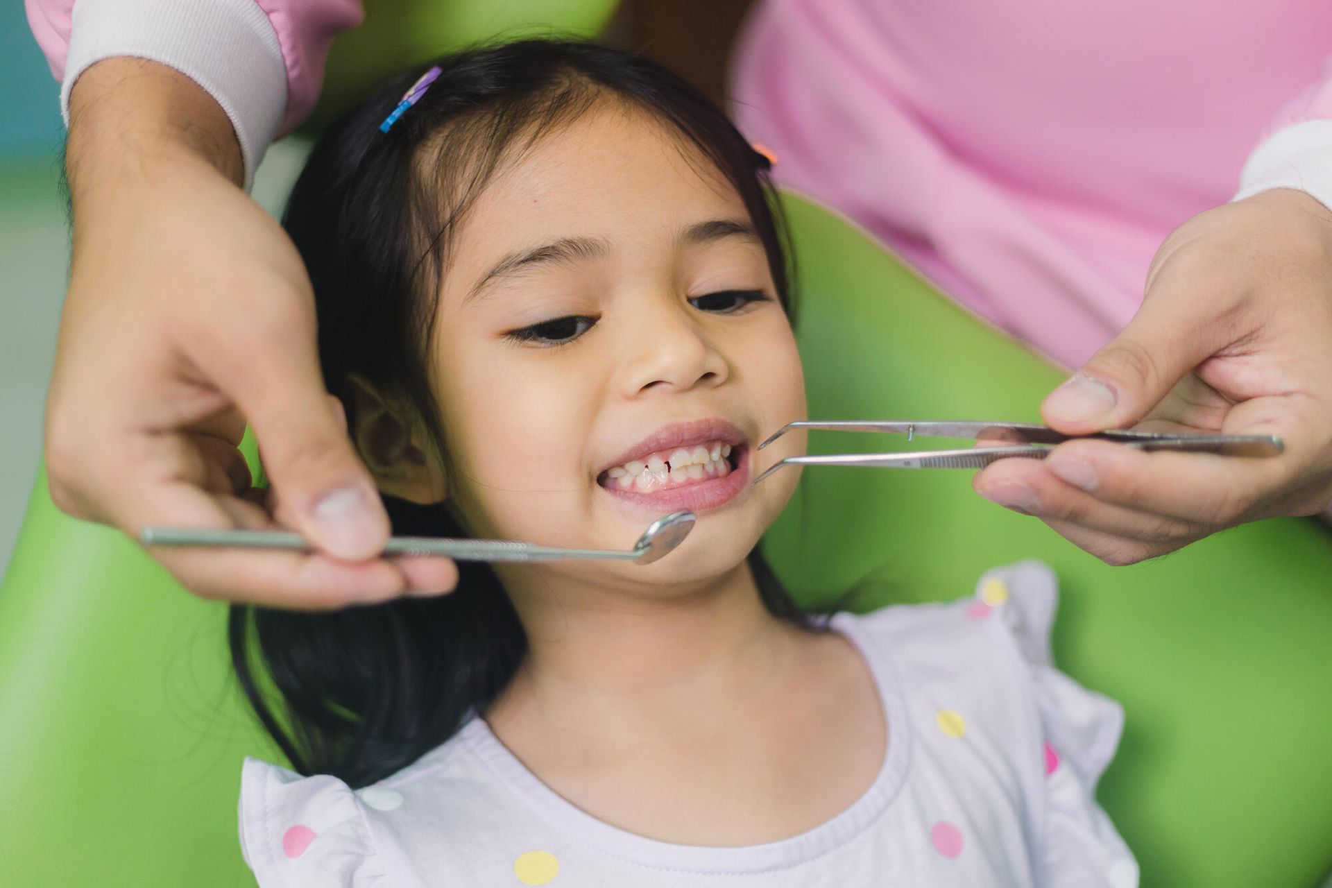 A little girl is getting her teeth examined by a dentist.