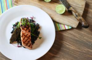 A white plate topped with a piece of meat and vegetables on a wooden table.