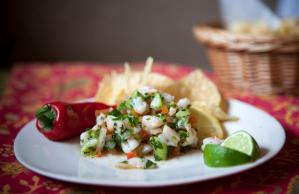 A plate of food with tortilla chips and a red pepper on a table.