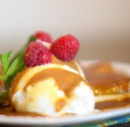 A close up of a dessert with raspberries on top on a plate.