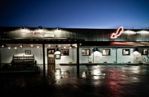 A building with a neon sign on the top of it is lit up at night.