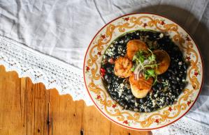 A bowl of food with shrimp and rice on a wooden table.