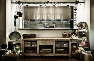 A black and white photo of a kitchen with a cat sleeping on the counter.