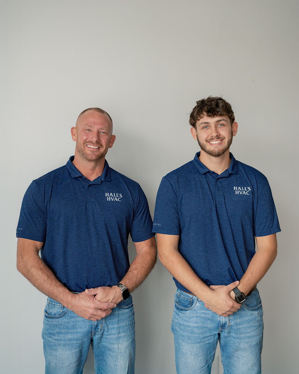 Man in blue shirt, smiling, behind a large HEIL air conditioning unit in a truck.