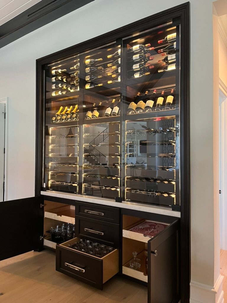 Wine storage cabinet with built-in racks, featuring various bottles and adjacent storage.