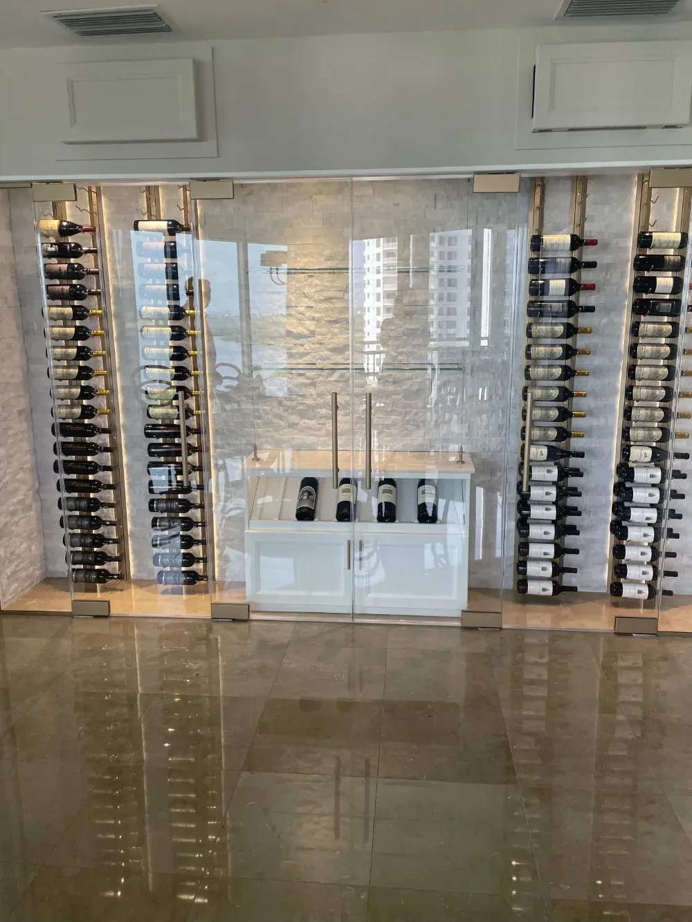 Glass of red wine next to bottle, blurred background of wine bottles and lights.