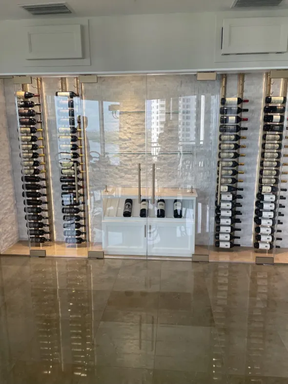 Glass of red wine next to bottle, blurred background of wine bottles and lights.