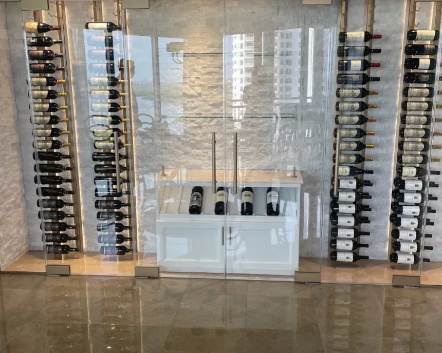 Wine bottles displayed in vertical racks with a white cabinet behind a glass enclosure.