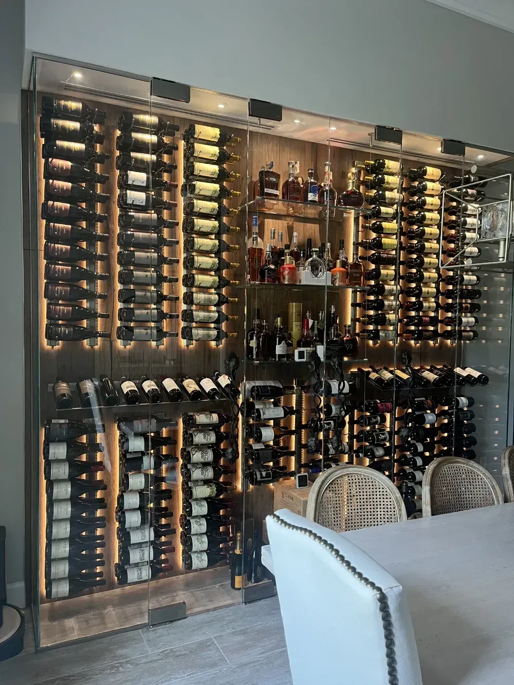 A built-in illuminated wine cellar with various wine bottles.