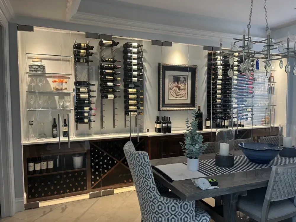 Dining room with wine storage. Bottles displayed in modern racks, below cabinets and beside a dining table.