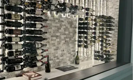 Glass of red wine next to bottle, blurred background of wine bottles and lights.