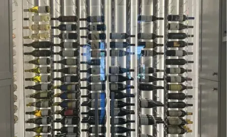 Glass of red wine next to bottle, blurred background of wine bottles and lights.