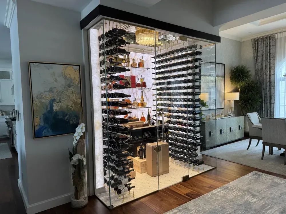 Wine cellar with glass walls, showcasing bottles on racks. Illuminated and built into a home.