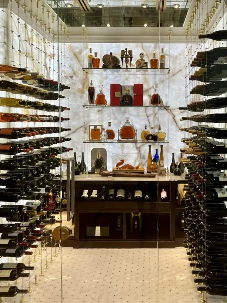 Wine cellar with glass door, marble accents, and rows of wine bottles.