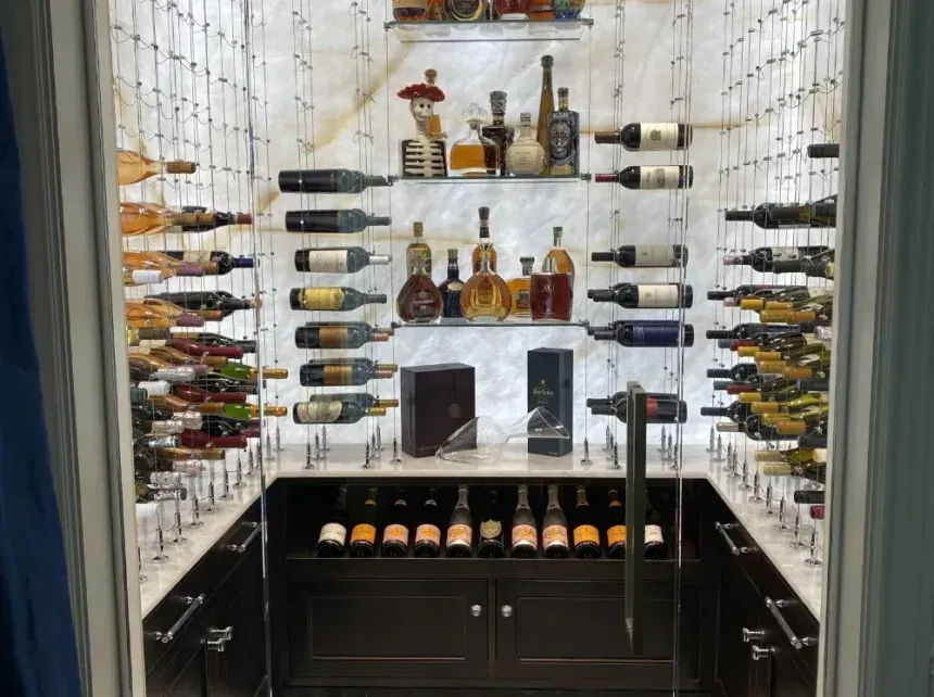 Wine cellar with bottles displayed on shelves and in cabinets, marble and dark wood interior.