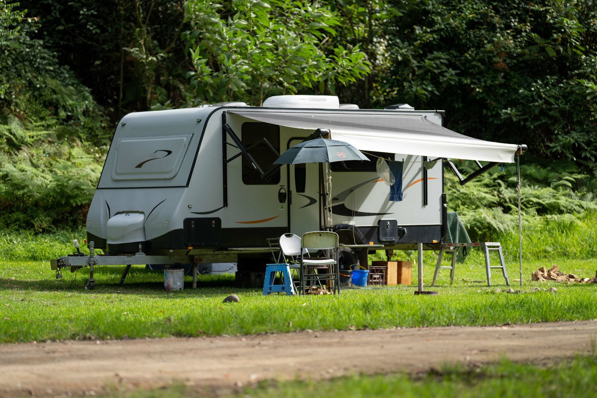 Un camping-car avec un auvent est garé dans un champ herbeux.