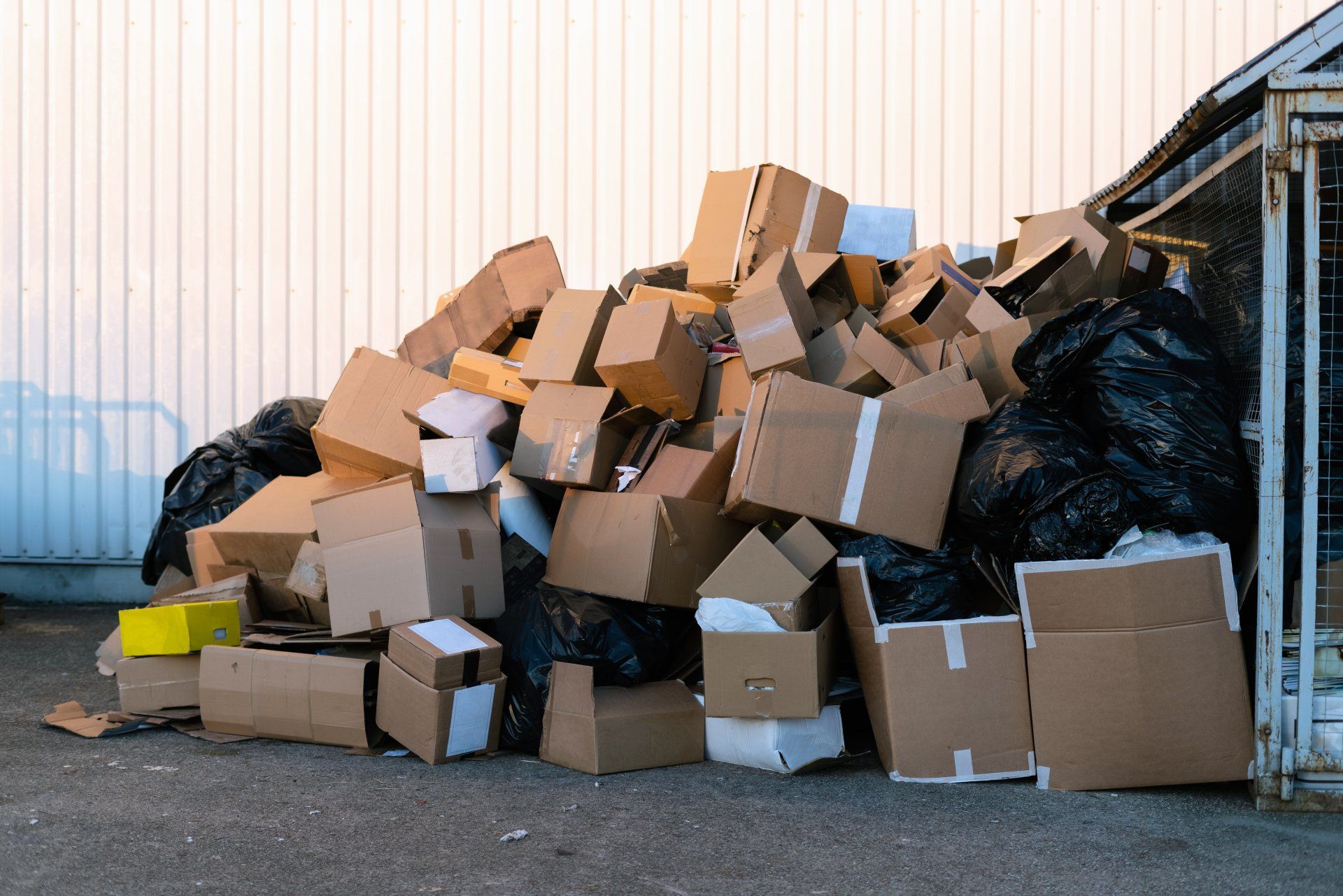Paper boxes next to a garbage bin. Stack of paper waste outdoor in the city. Paper recycling, nobody.